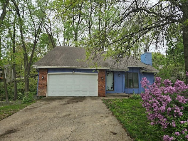 ranch-style house featuring a chimney, brick siding, a shingled roof, driveway, and an attached garage