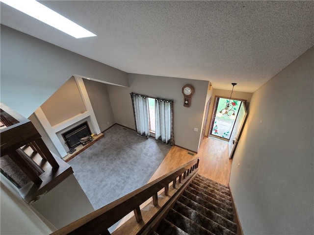 unfurnished living room with a textured ceiling, a fireplace with raised hearth, and stairs