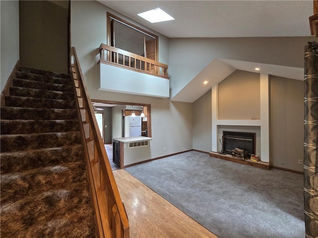unfurnished living room featuring recessed lighting, stairway, a glass covered fireplace, baseboards, and a skylight