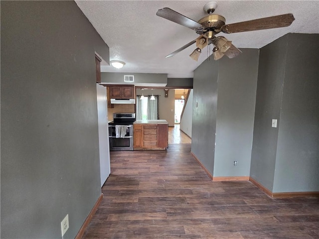 interior space with visible vents, baseboards, range with two ovens, dark wood finished floors, and a ceiling fan