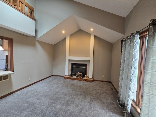 unfurnished living room with a fireplace with raised hearth, vaulted ceiling, carpet, and baseboards