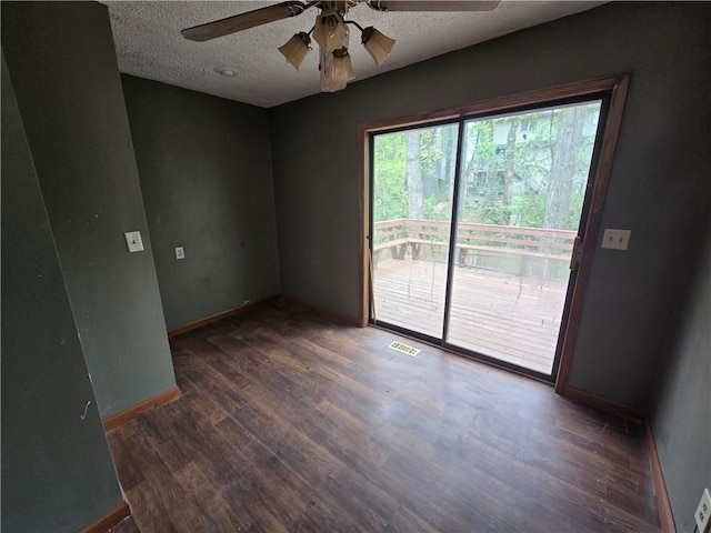 empty room with visible vents, ceiling fan, wood finished floors, and baseboards