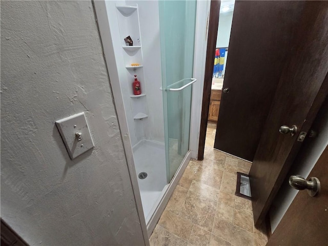 full bath featuring stone finish floor, a shower stall, and built in shelves