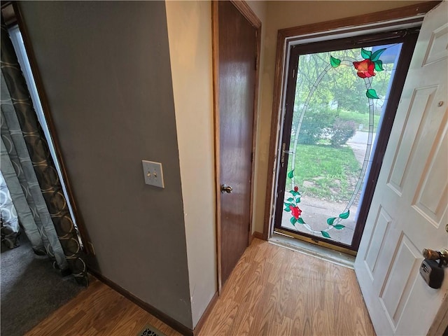 doorway featuring light wood-style flooring and baseboards