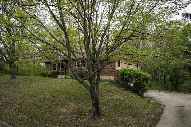 view of front facade featuring a front lawn, concrete driveway, and brick siding