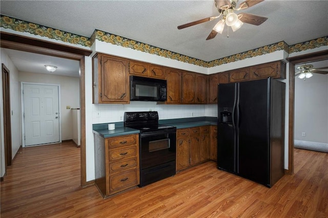 kitchen featuring black appliances, dark countertops, ceiling fan, and light wood-style floors