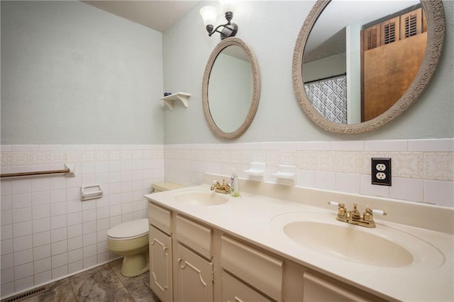 full bath featuring toilet, tile walls, a sink, and visible vents