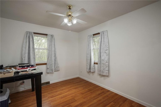 office area featuring ceiling fan, baseboards, wood finished floors, and a healthy amount of sunlight