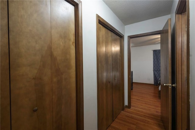 hall featuring a textured ceiling and wood finished floors