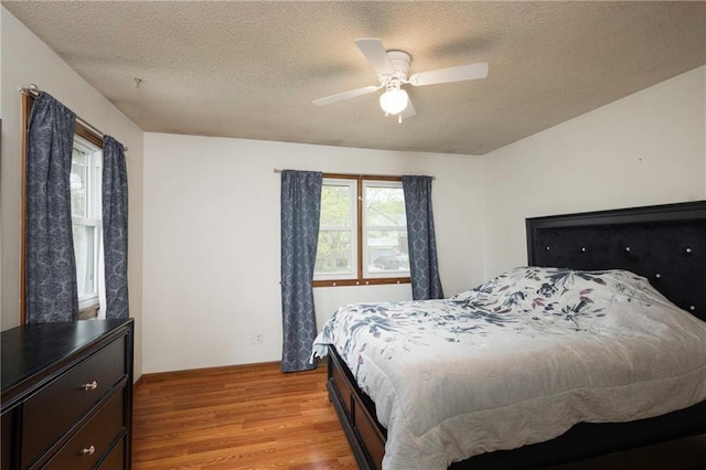 bedroom with ceiling fan, a textured ceiling, and light wood finished floors