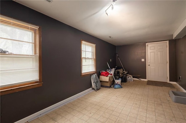 recreation room featuring light floors, track lighting, and baseboards