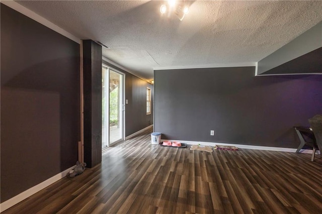 unfurnished living room with a textured ceiling, wood finished floors, and baseboards