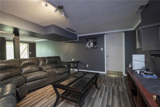 living area with a textured ceiling, wood finished floors, visible vents, and baseboards