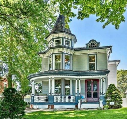 victorian home with a porch and a front lawn
