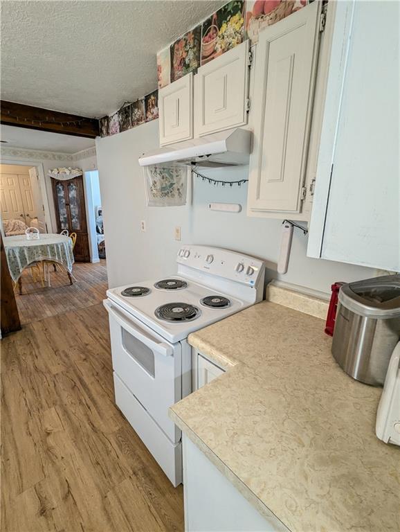 1539 1st Ave W, Horton, KS 66439 - kitchen with light wood finished floors, under cabinet range hood, white range with electric stovetop, light countertops, and white cabinets