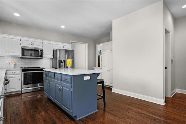 5510 W 153rd Ter, Overland Park, KS 66223 - kitchen with appliances with stainless steel finishes, blue cabinetry, white cabinetry, baseboards, and dark wood-style floors