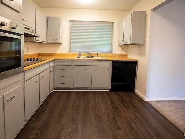 kitchen featuring light countertops, under cabinet range hood, a sink, dark wood finished floors, and black appliances