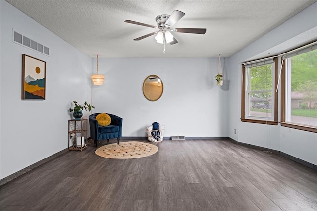 living area with a ceiling fan, a textured ceiling, visible vents, and wood finished floors