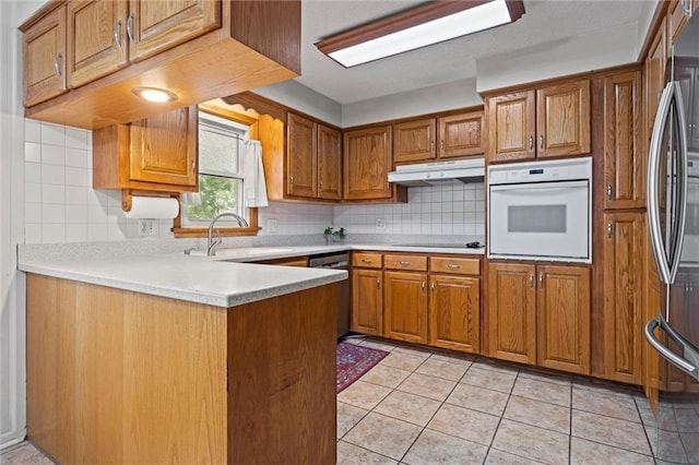 kitchen featuring brown cabinetry, a sink, appliances with stainless steel finishes, and under cabinet range hood