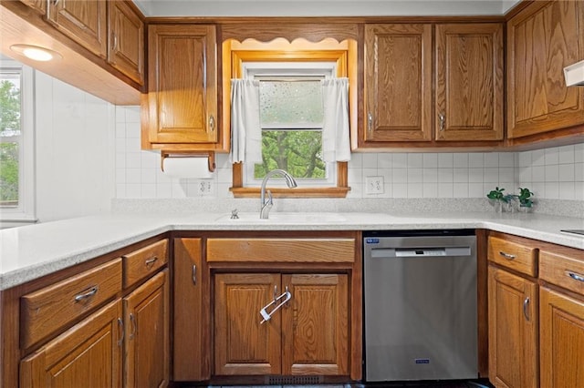 kitchen featuring a sink, dishwasher, brown cabinets, and light countertops