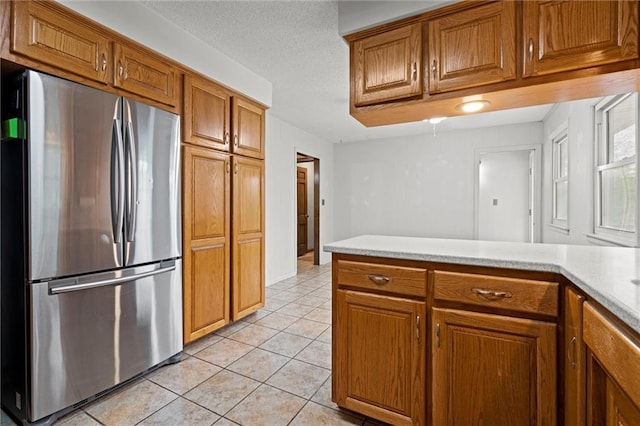 kitchen featuring light countertops, freestanding refrigerator, and brown cabinets