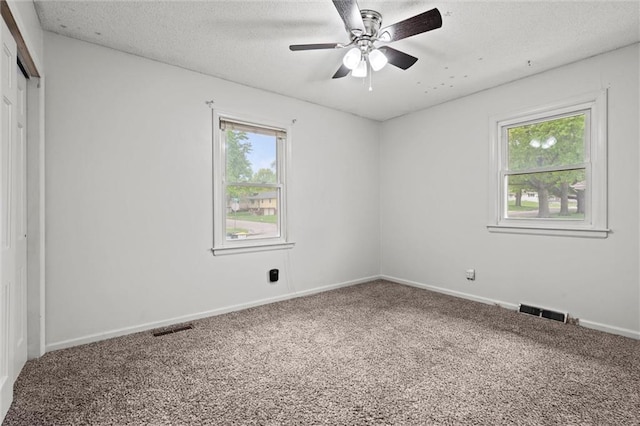 empty room with ceiling fan, visible vents, baseboards, and carpet