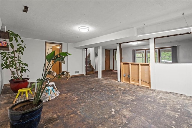 basement featuring stairs, a textured ceiling, and visible vents