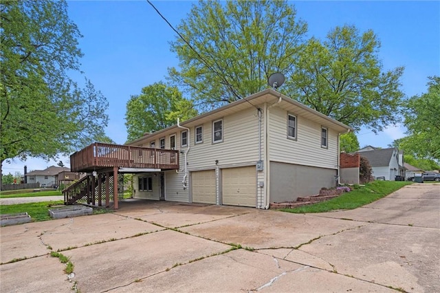 view of side of home with a deck, an attached garage, driveway, and stairs