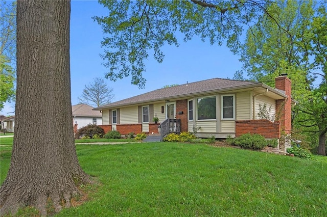 ranch-style house with a chimney, a front yard, and brick siding