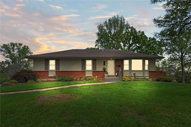 view of front of home featuring a lawn and brick siding