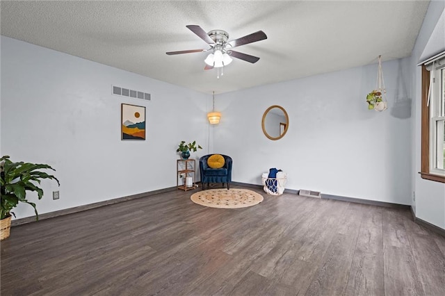 living area featuring baseboards, a ceiling fan, wood finished floors, and visible vents