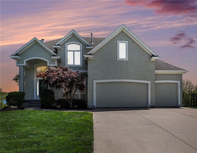 traditional home with roof with shingles, an attached garage, stucco siding, concrete driveway, and a lawn