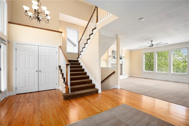 entryway with stairway, baseboards, ceiling fan with notable chandelier, and wood finished floors