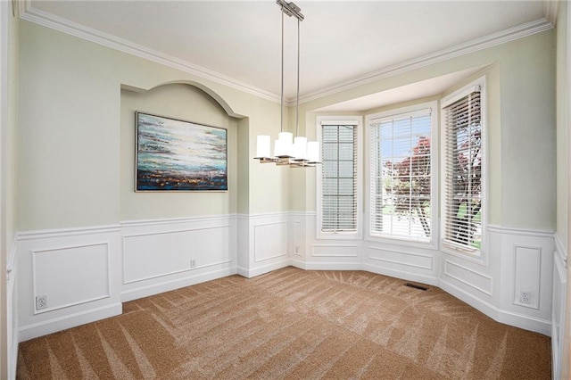 unfurnished dining area featuring visible vents, crown molding, wainscoting, carpet floors, and an inviting chandelier
