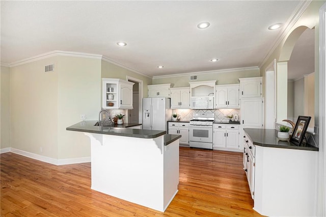 kitchen with white appliances, a peninsula, open shelves, and dark countertops