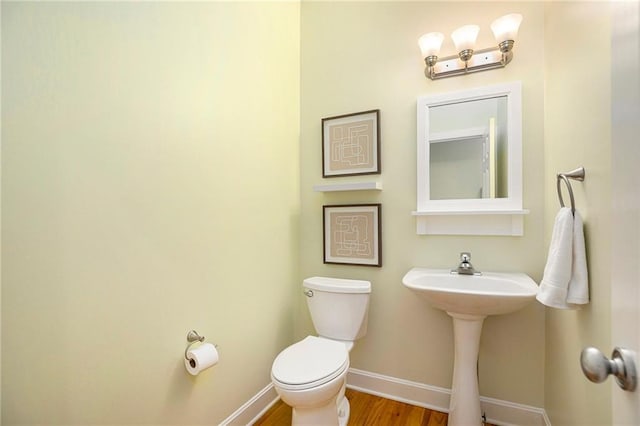 bathroom featuring toilet, baseboards, and wood finished floors