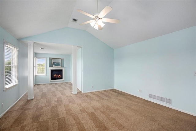 interior space with visible vents, ceiling fan, vaulted ceiling, and a lit fireplace