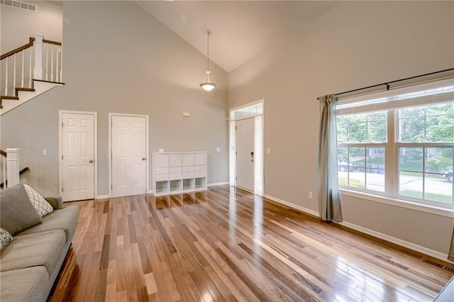 18716 W 164th Ter, Olathe, KS 66062 - unfurnished living room featuring high vaulted ceiling, light wood-style flooring, stairs, and baseboards