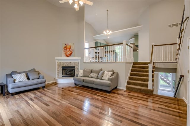 18716 W 164th Ter, Olathe, KS 66062 - living area with wood finished floors, high vaulted ceiling, a ceiling fan, stairs, and a glass covered fireplace