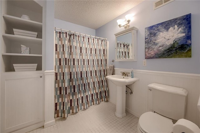 18716 W 164th Ter, Olathe, KS 66062 - bathroom featuring toilet, a wainscoted wall, a textured ceiling, curtained shower, and tile patterned floors