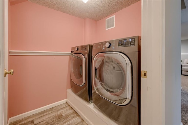 18716 W 164th Ter, Olathe, KS 66062 - laundry area with washing machine and clothes dryer, a textured ceiling, wood finished floors, and baseboards