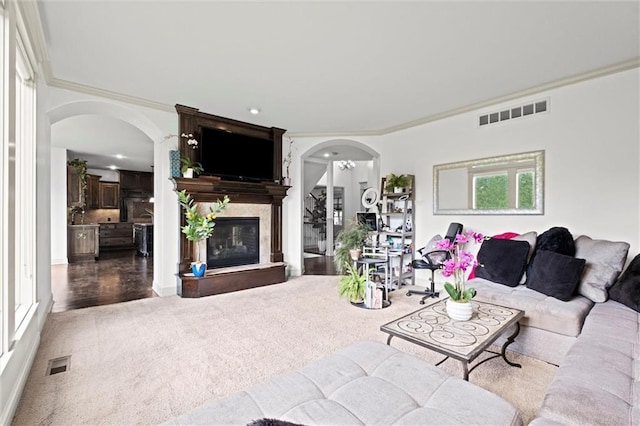 living area with arched walkways, a premium fireplace, ornamental molding, wood finished floors, and recessed lighting