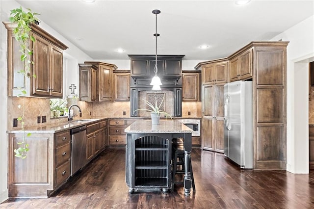 kitchen with stainless steel appliances, a sink, dark wood-type flooring, light stone counters, and recessed lighting