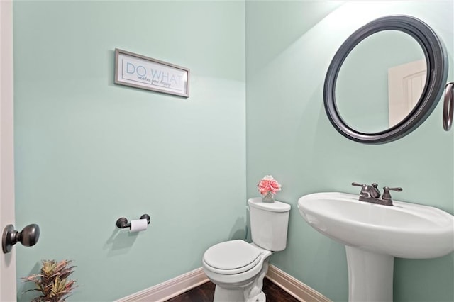 bathroom with wood finished floors, baseboards, toilet, and a sink