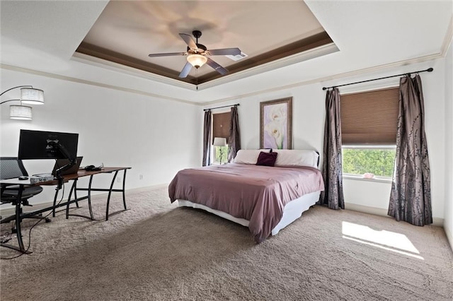 bedroom with a tray ceiling, ornamental molding, carpet floors, an office area, and ceiling fan