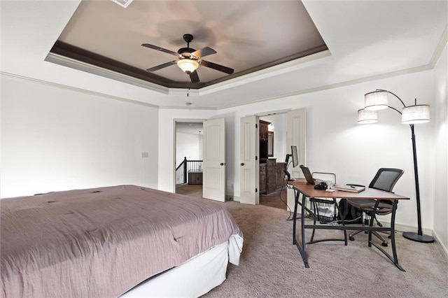 bedroom featuring a tray ceiling, crown molding, carpet, an office area, and baseboards