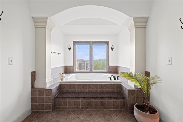 bathroom with ornate columns, a bath, and tile patterned floors