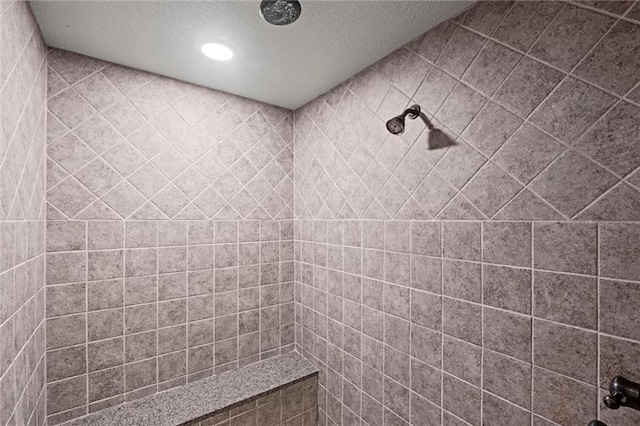 bathroom with a textured ceiling, a tile shower, and recessed lighting