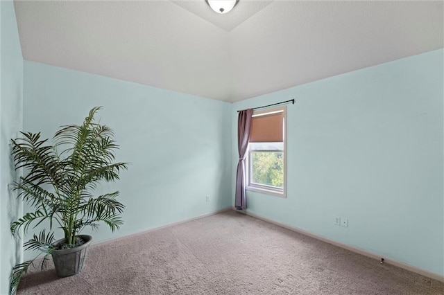 carpeted empty room featuring vaulted ceiling