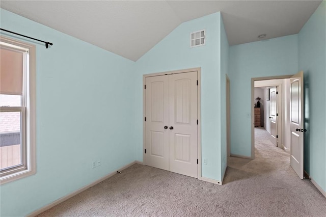 unfurnished bedroom with carpet flooring, vaulted ceiling, a closet, and baseboards